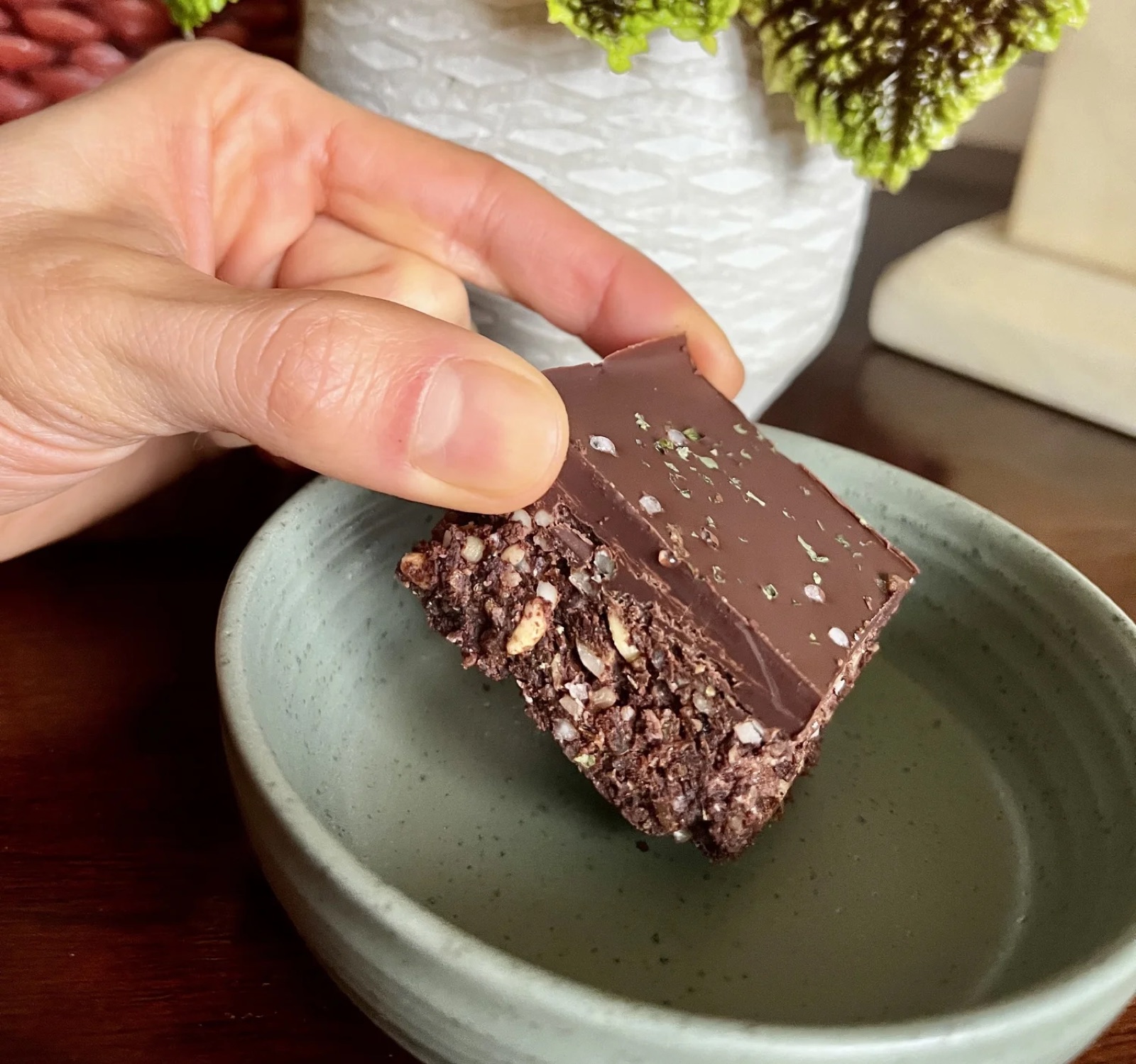 Nori and miso brownie held over a speckled dish