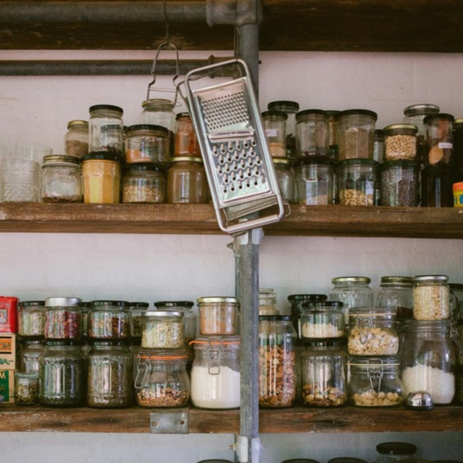A lived-in pantry of glass jars filled with grains, pulses and spices
